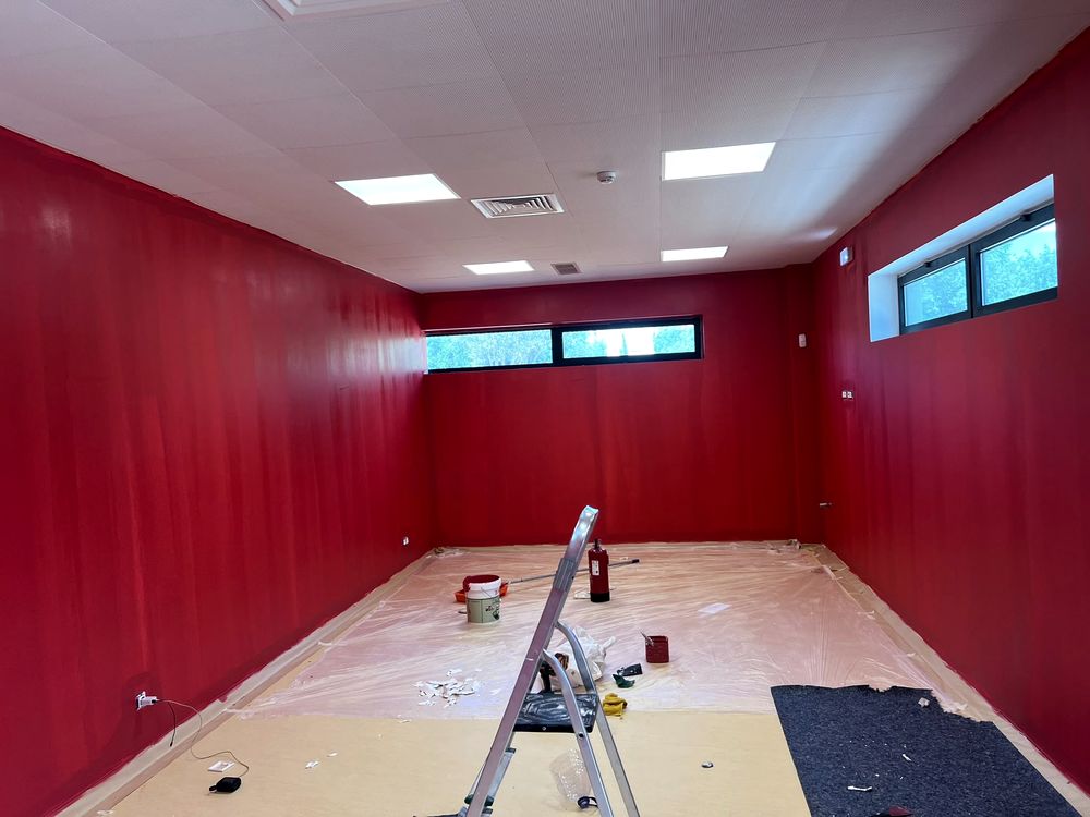 Pintura de parede em curso, com escada e proteção no chão